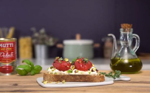 peeled tomatoes on crostone with burrata cheese and pistachios